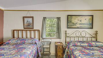 A bedroom with two beds, a desk, and a window.