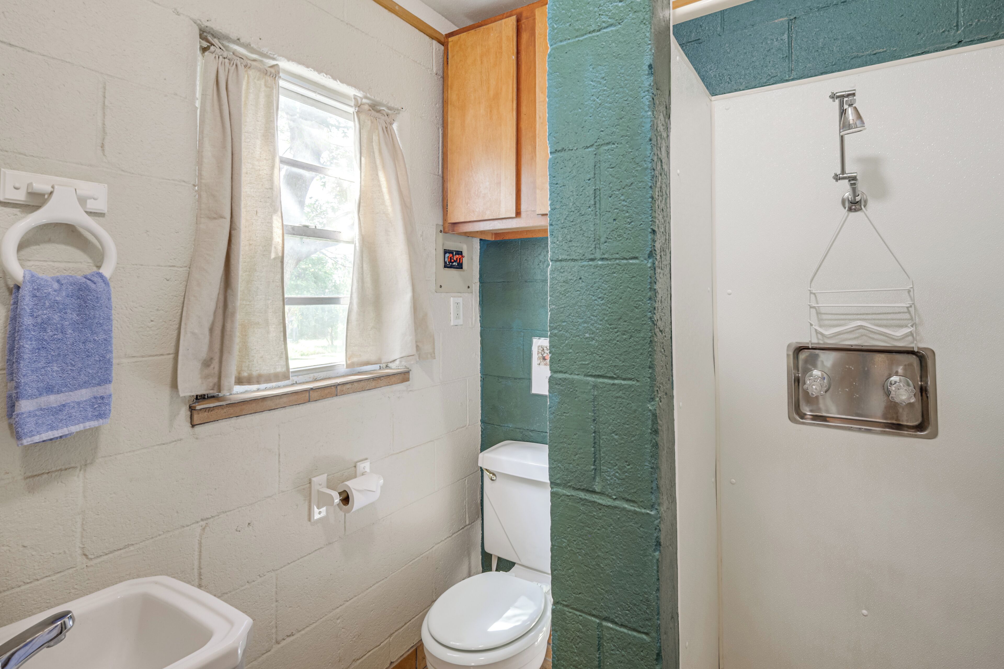 A bathroom with a toilet, sink, and shower.
