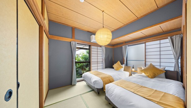 A traditional Japanese-style bedroom with two beds, tatami flooring, shoji screens, and a hanging paper lantern.