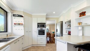 Une cuisine moderne avec des meubles blancs, un four encastré, un four à micro-ondes et un lave-vaisselle.