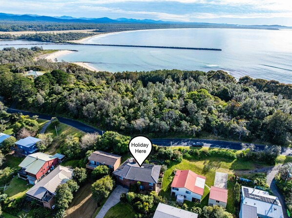 Vue aérienne d’une zone résidentielle côtière, avec des maisons, une route et une plage.