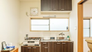 Une cuisine de taille réduite, dotée de meubles en bois, d’un four à micro-ondes, d’une cuisinière et d’une fenêtre située au-dessus de l’évier.