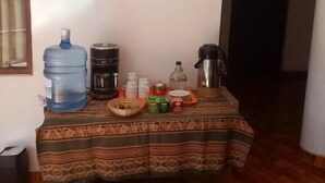 A small dining area with a table set for two, featuring a water dispenser, coffee maker, and various condiments. - Hostal Aylluq Wasin  (Urubamba)