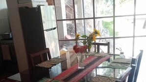 Un comedor con una mesa de vidrio, mantel estampado y sillas de madera.