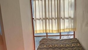 A room with a bed, a window with sheer curtains, and a patterned pillow. - Hostal Aylluq Wasin  (Urubamba)