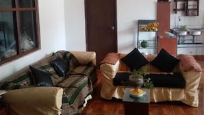 A living room with two sofas, a coffee table, and a kitchen area in the background. - Hostal Aylluq Wasin  (Urubamba)