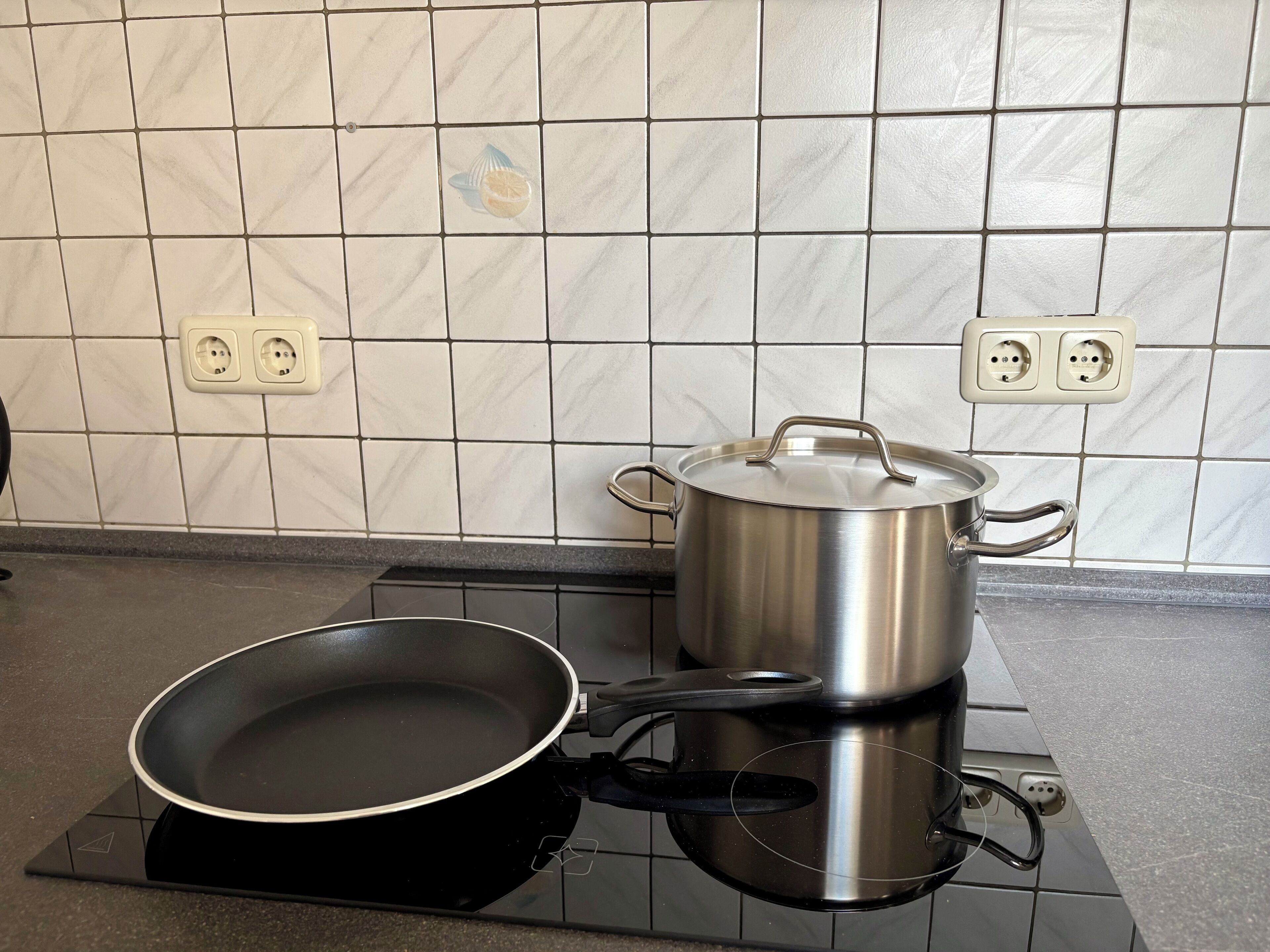 Une cuisine équipée d’une cuisinière, d’une poêle et d’une casserole sur la plaque de cuisson à induction.