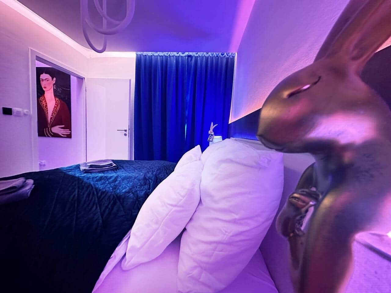 Ein Zimmer mit einem Bett, einem blauen Vorhang und einer Wandleuchte.