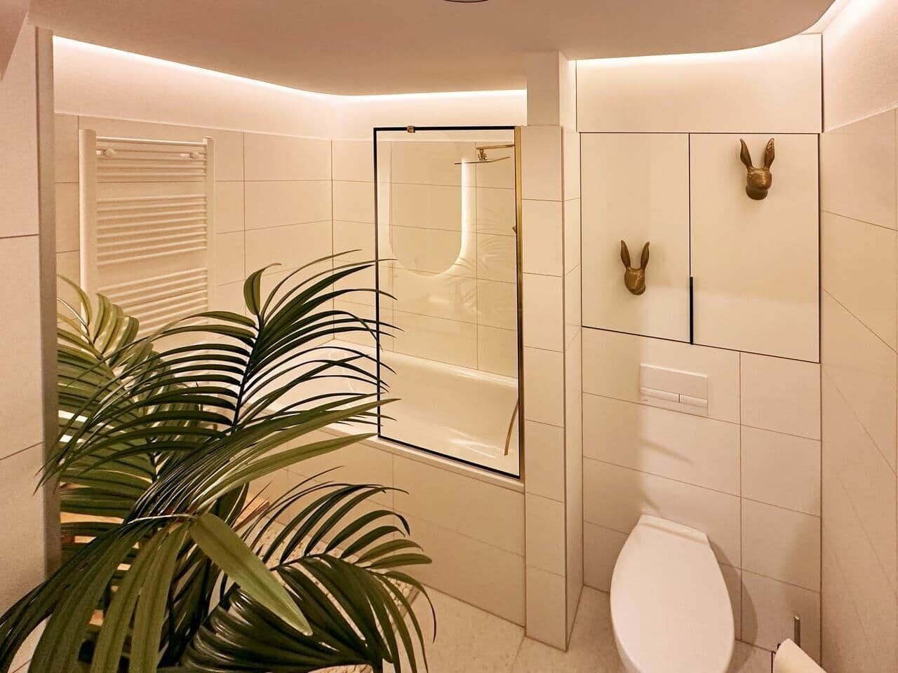 Une salle de bain moderne dotée d’une douche à parois de verre, de toilettes et d’un mur décoratif orné de motifs représentant des têtes d’animaux.