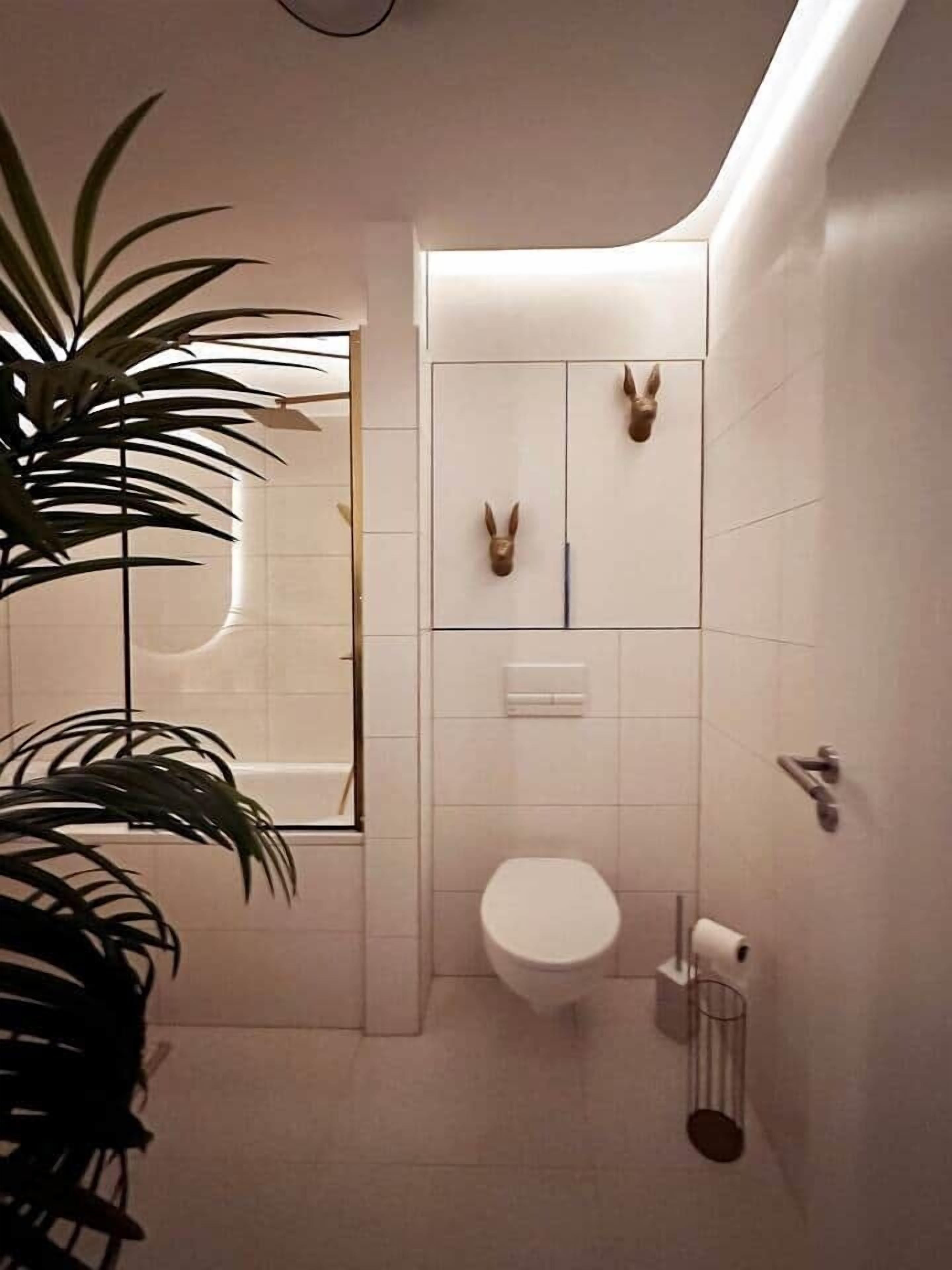 A modern bathroom with a white toilet, a mirror, and a sink.