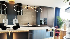 A modern kitchen with a central island, pendant lighting, and a view of a dining area. - Ambient lounge with sundeck and free parking (Bratislava)