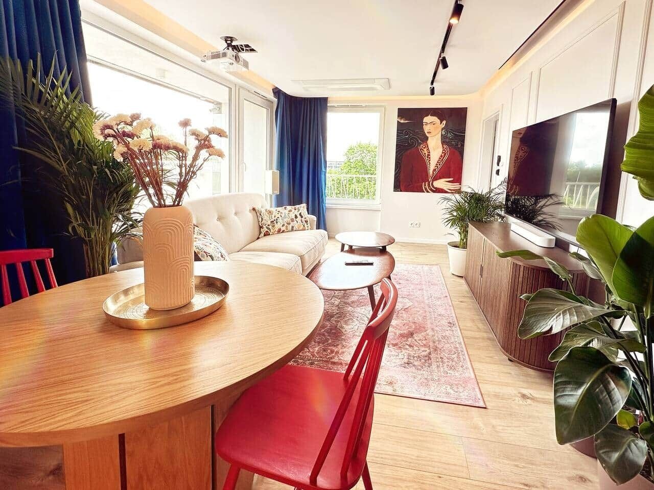 Een moderne woonkamer met een eethoek, een bank, een televisie en grote ramen.