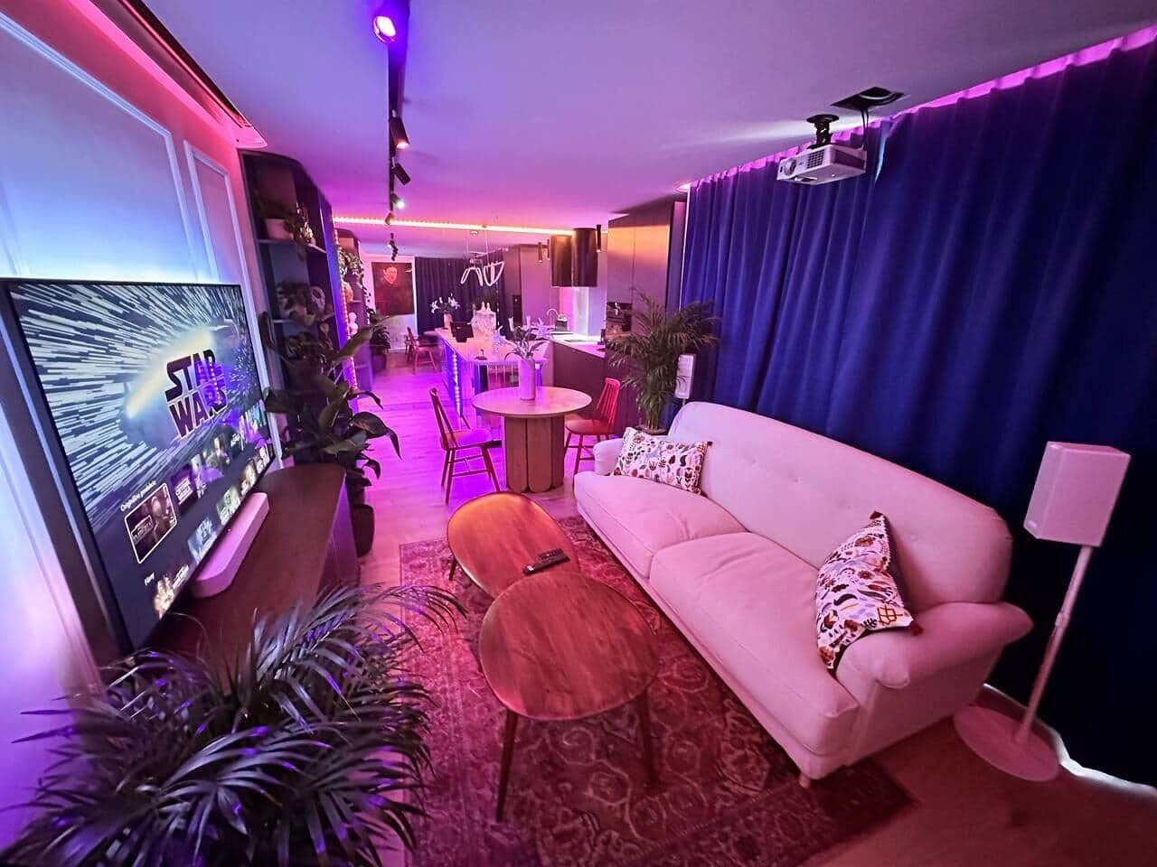 A modern living room with a sofa, coffee table, TV, and a projector.