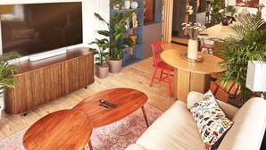 A modern living room with a flat-screen TV, wooden coffee table, red chairs, and a sofa with a patterned pillow. - Ambient lounge with sundeck and free parking (Bratislava)