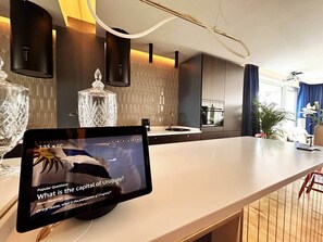 A modern kitchen with a tablet displaying a video, a large island, and a view of the living area.