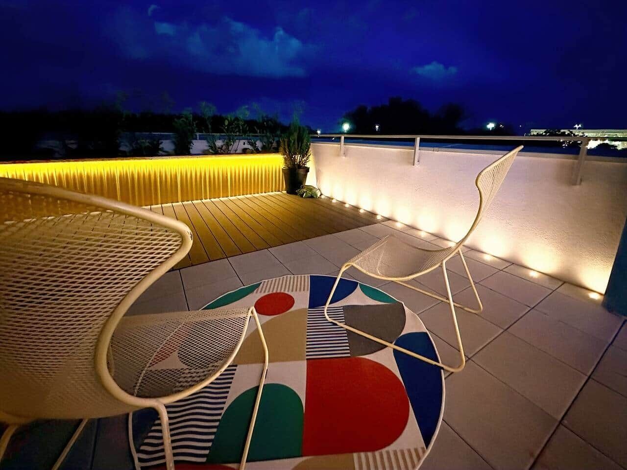Een terras op het dak met een zwembad, stoelen en een kleurrijk vloerontwerp.