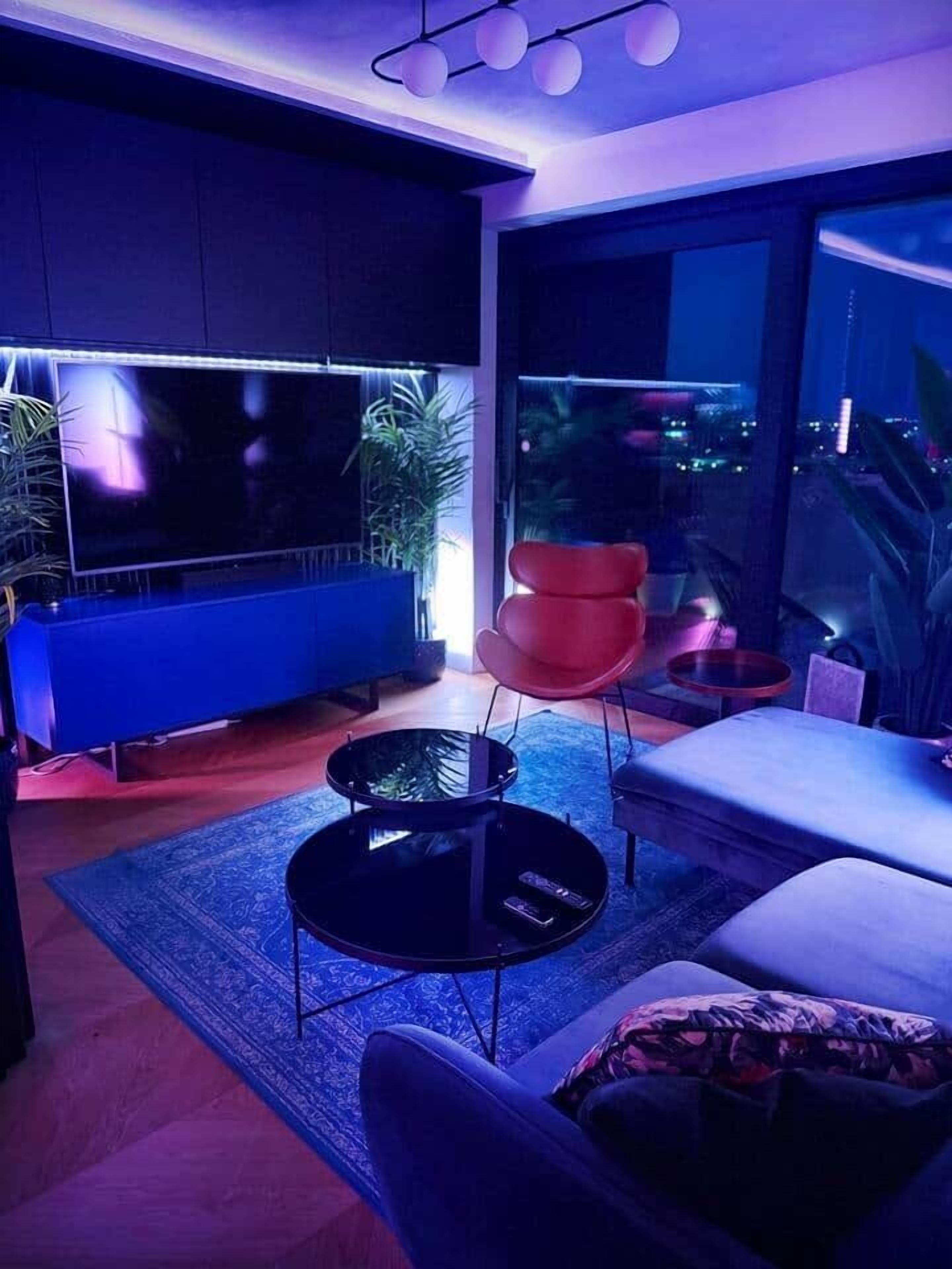 A modern living room with a large TV, a round coffee table, and a red chair.