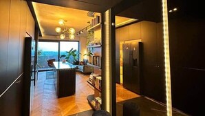 Une cuisine moderne dotée d’un îlot central, d’appareils électroménagers intégrés et offrant une vue sur l’extérieur.