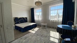 A hotel room with a bed, a round table, and a chandelier. - Paradise Villa (Taldykorgan)