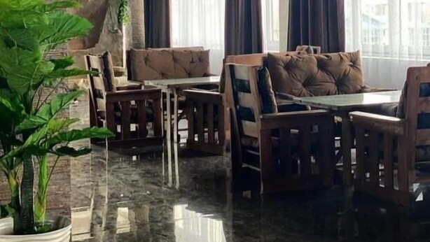 A dining area with a stone wall, a chandelier, and large windows with curtains. - Paradise Villa (Taldykorgan)