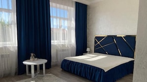 A bedroom with a bed, a round table, and a window with curtains. - Paradise Villa (Taldykorgan)