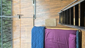 Una habitación compacta con cama, una silla, una mesita y una ventana con cortinas.