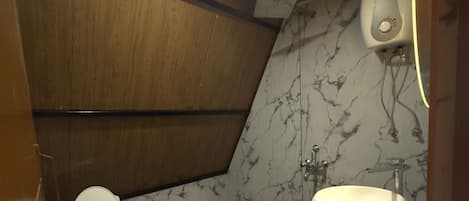 Un baño pequeño y funcional con inodoro, lavamanos y pared de mármol.