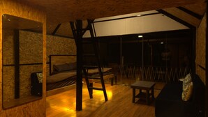 Un acogedor dormitorio en el ático con cama de altillo, escalera de madera, una mesita y un sofá.