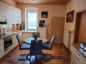 A compact kitchen with a dining area, a microwave, a coffee maker, and a potted plant on the table.