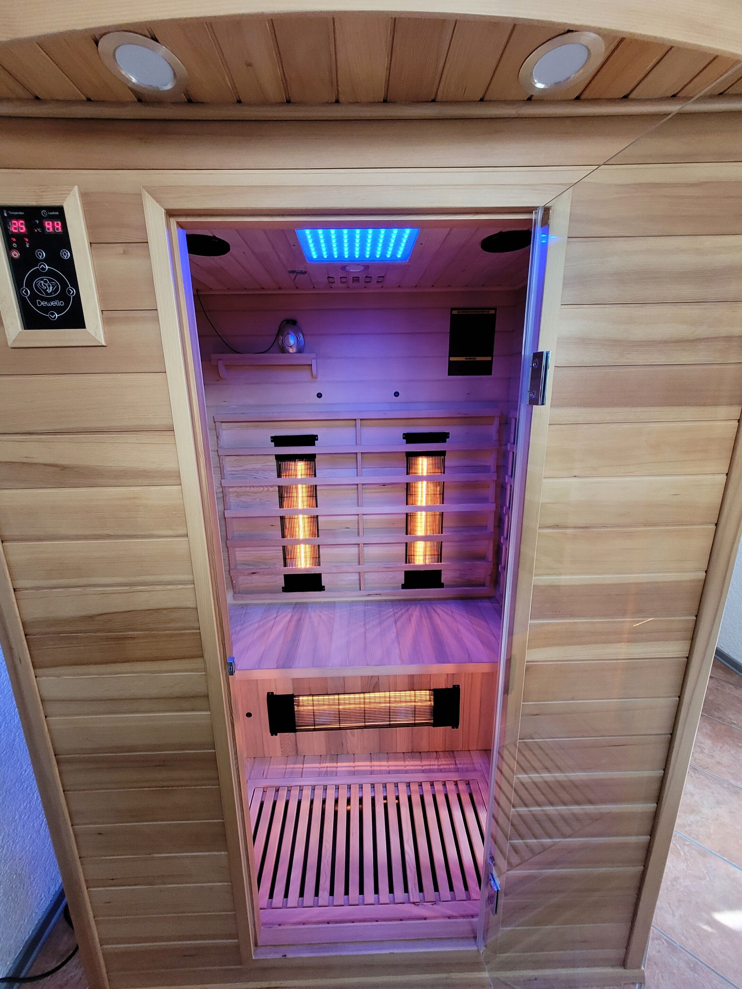 A sauna with wooden walls, a control panel, and two visible heating elements.