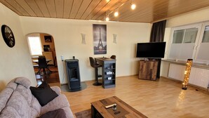 A living room with a sofa, a coffee table, a TV, a fireplace, and a dining area with chairs and a table.