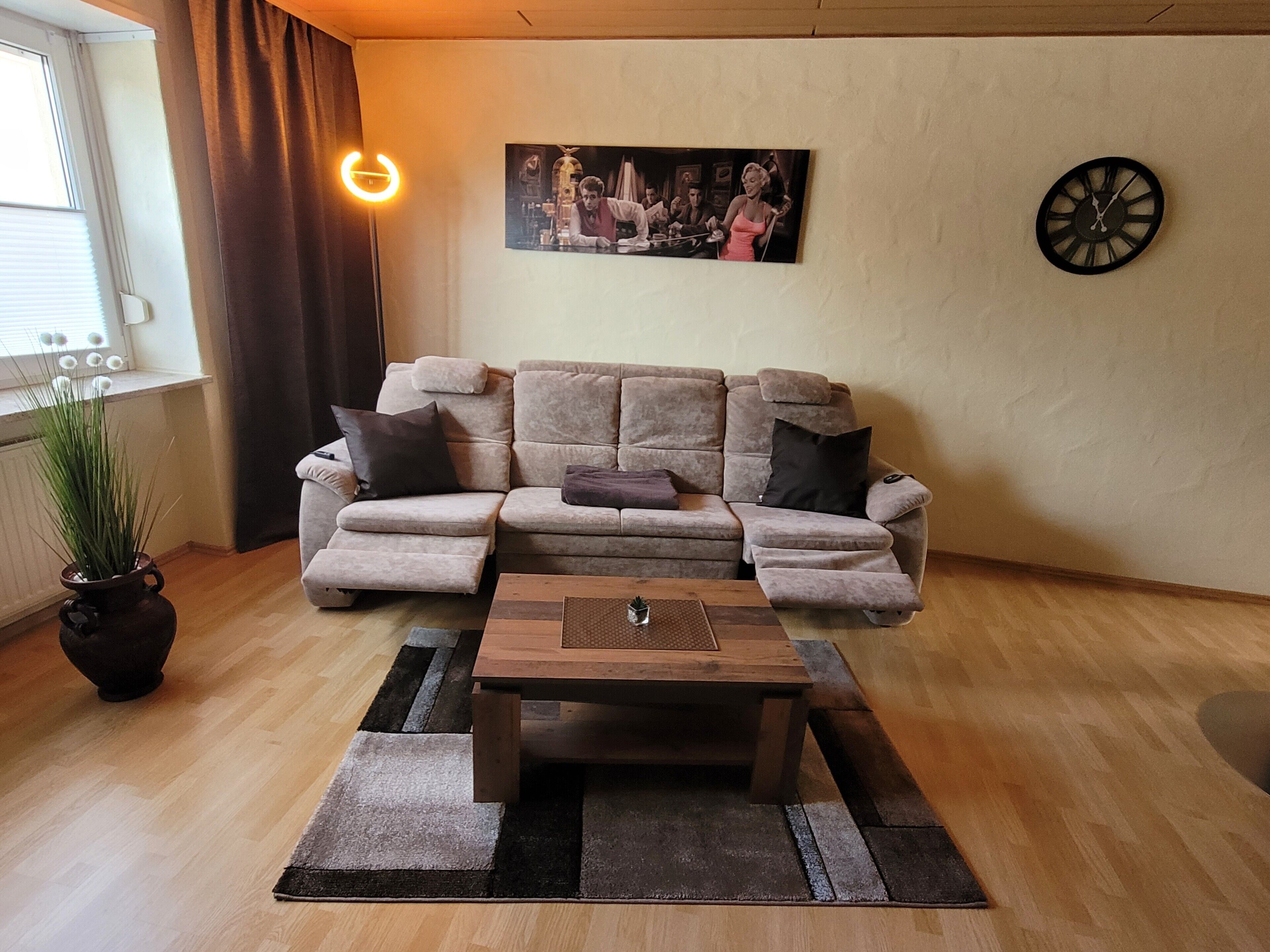 A living room with a sectional sofa, a coffee table, a clock, and a framed picture on the wall.
