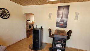 A modern living room with a dining area, a kitchen in the background, and a large Eiffel Tower poster on the wall.