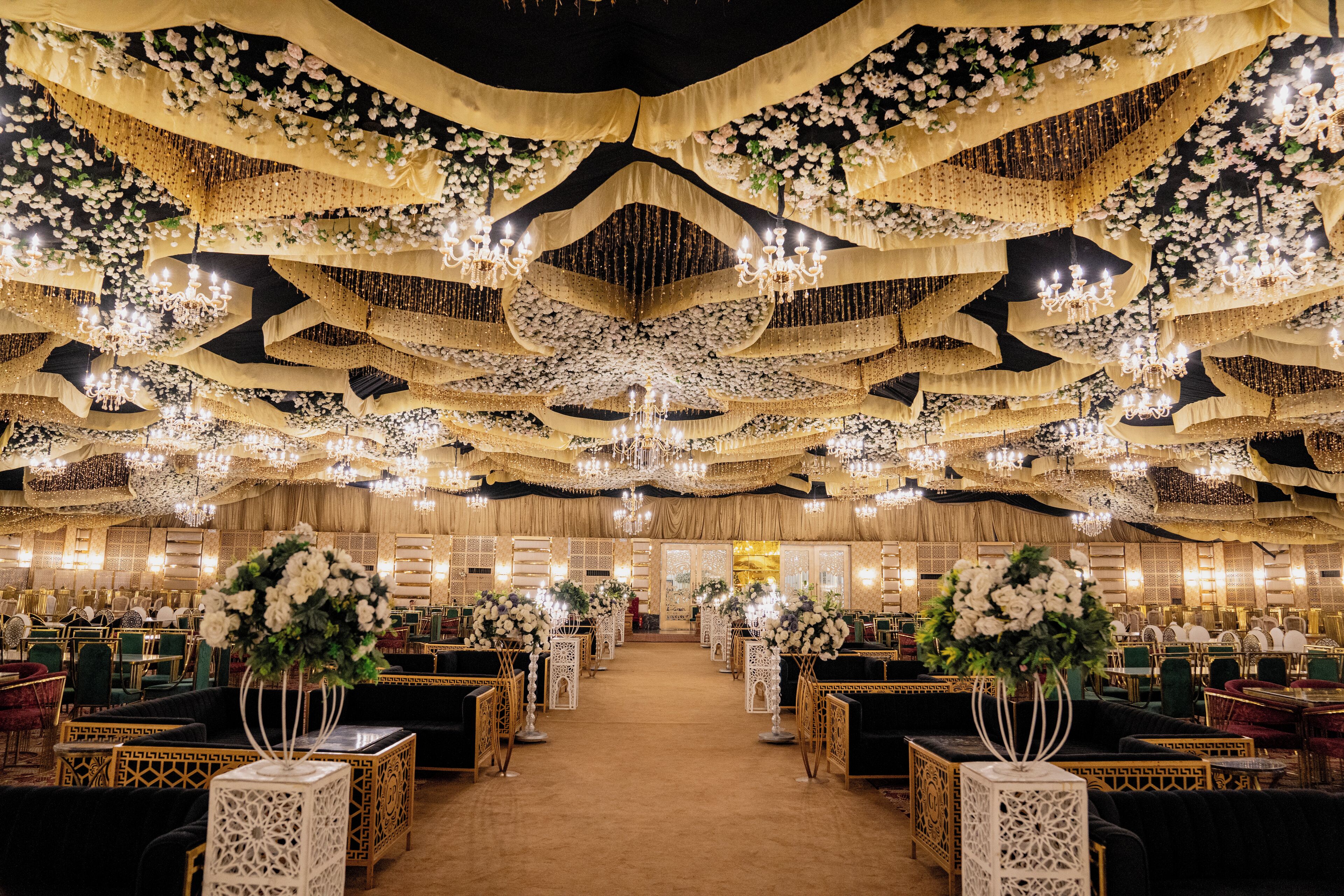 A banquet hall with tiered seating, chandeliers, and floral decorations.
