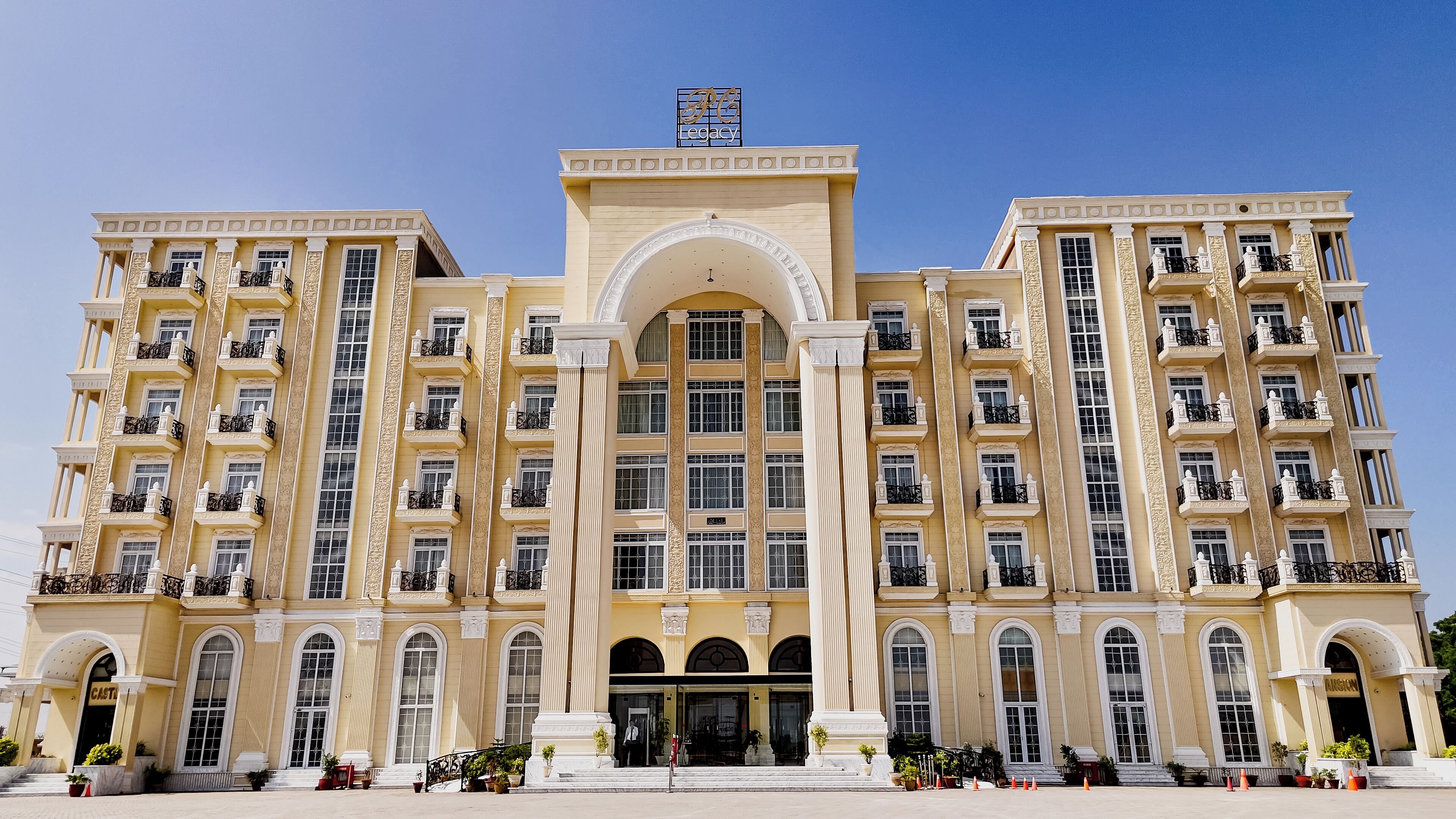 Un hotel grande de varios pisos con una entrada central, balcones y un letrero que dice 'FC Legacy'.