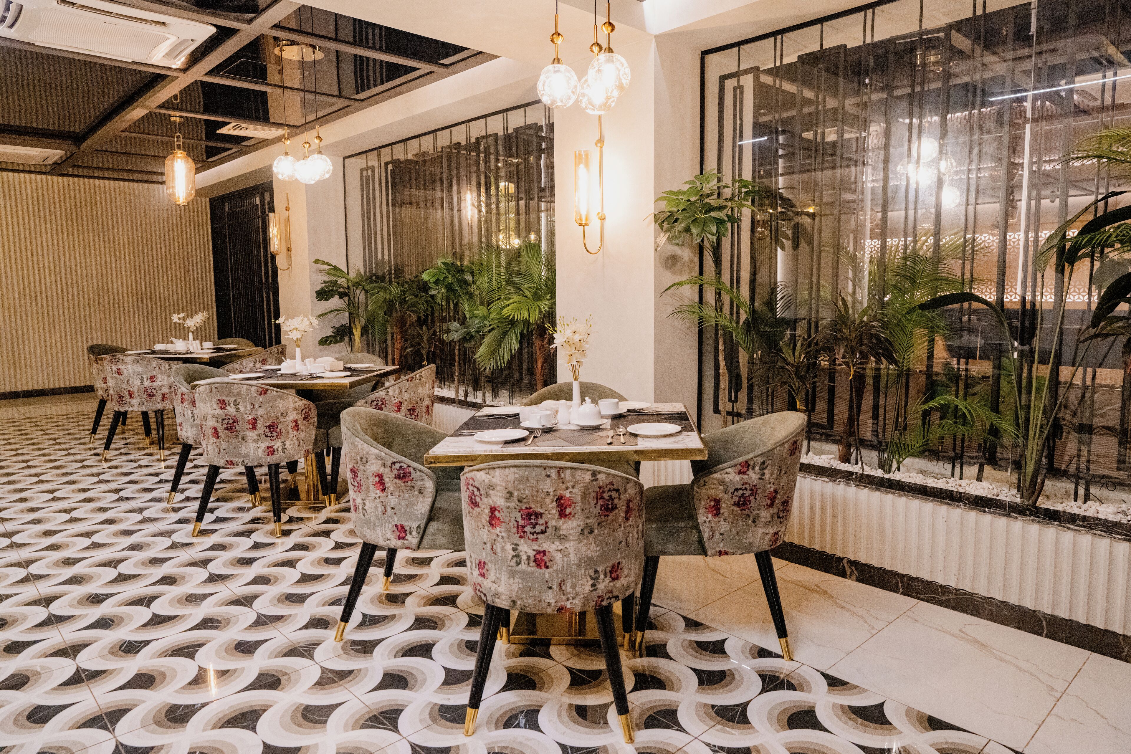 A dining area with round tables, floral upholstered chairs, and a patterned floor.