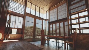 A traditional Japanese-style room with tatami flooring, wooden furniture, and large windows with shoji screens. - Farming Resort San San Villa (Awaji)