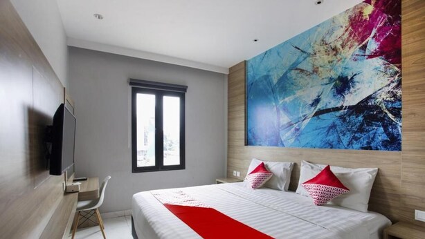 Een moderne hotelkamer met een groot bed, een bureau en een televisie.