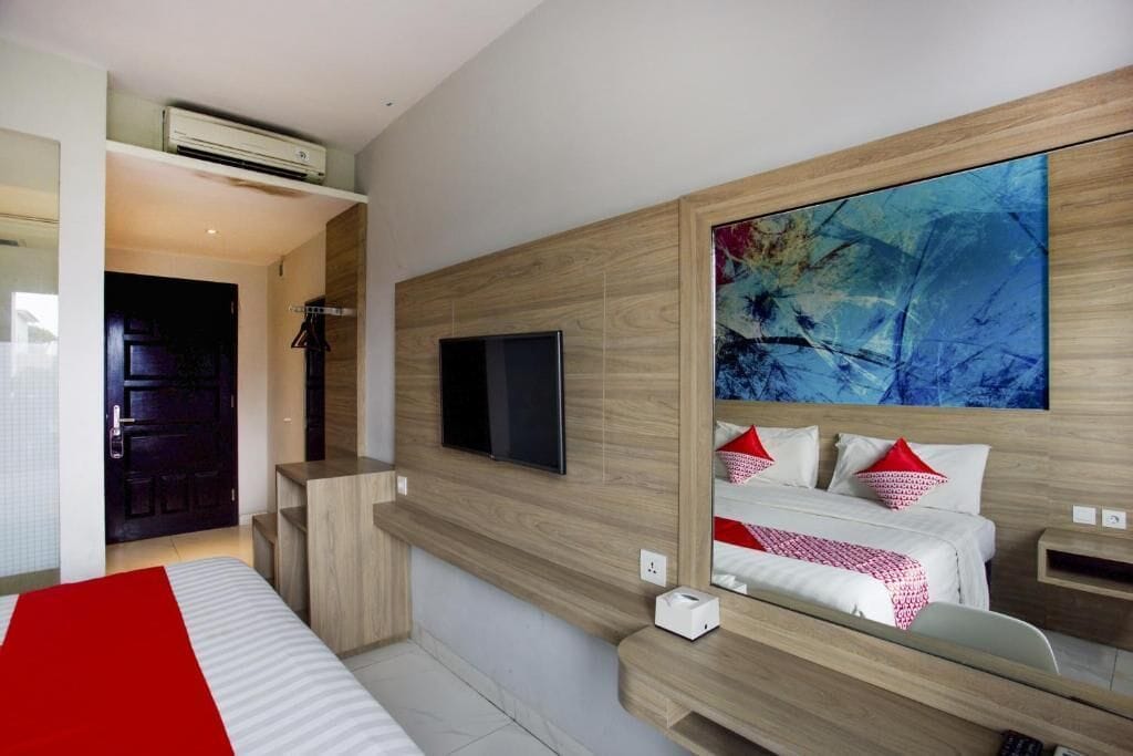 A modern hotel room with a large bed, a mounted TV, and a large abstract painting on the wall.