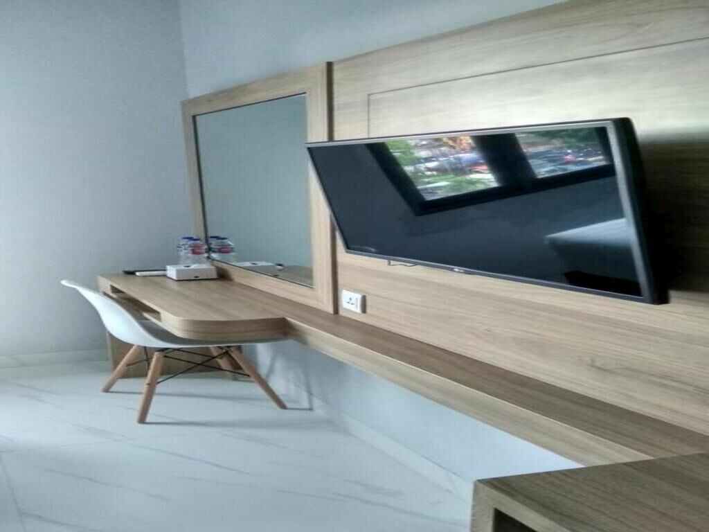 A modern room with a flat-screen TV mounted on a wooden wall, a desk with a chair, and a small table.