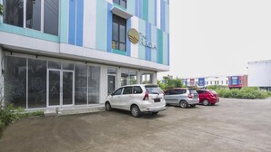 Un edificio con un letrero que dice 'The REGA' y un estacionamiento con varios autos.