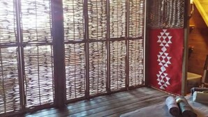A room with a wooden floor, a metal partition with a geometric pattern, and a red wall with a white geometric design.