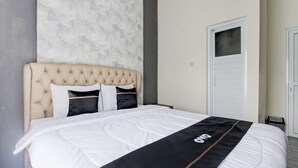 A neatly made bed with a white and black bedspread, a tufted headboard, and a marble wall behind it. - Capital O Sudirto Villa Dan Homestay Dieng (Wonosobo)
