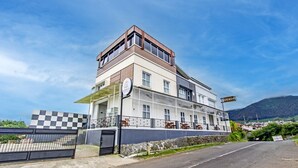 A multi-story building with a checkered gate, a balcony, and a sign reading "SUDIRTO." - Capital O Sudirto Villa Dan Homestay Dieng (Wonosobo)