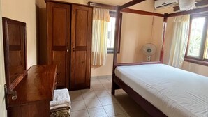 A room with a bed, a desk, a chair, a wardrobe, and a ceiling fan. - Ocean Walk Guesthouse (Brufut)