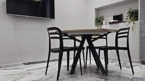 A dining area with a round table and four chairs, a flat-screen TV mounted on the wall, and a shelf with plants and a bottle. - Feffo's home (Roma)