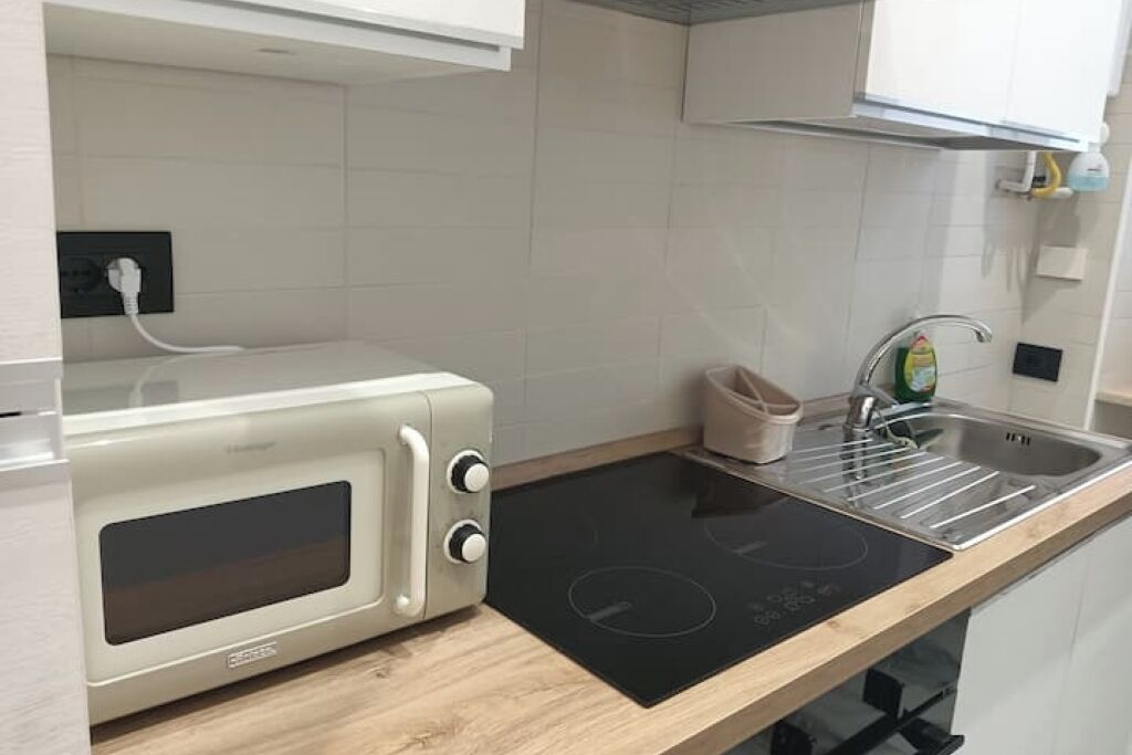 Une cuisine équipée d’un four à micro-ondes, d’un évier et d’une plaque de cuisson à induction noire.