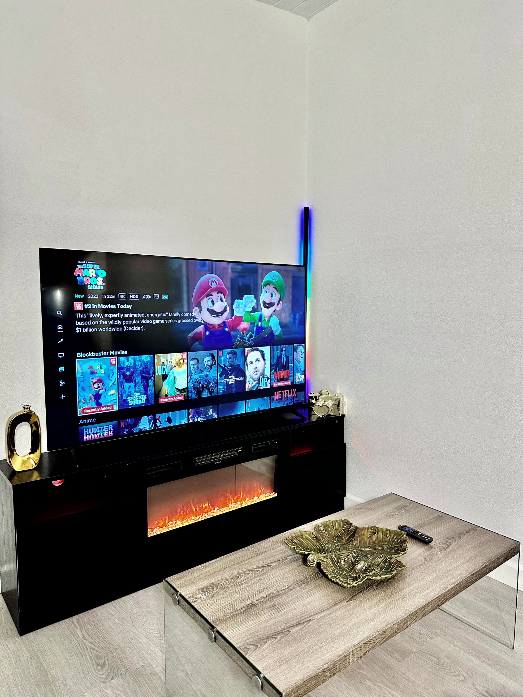 A flat-screen TV on a black stand with a wooden table in front.