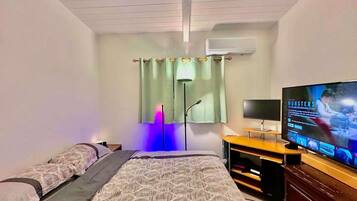 A bedroom with a bed, a TV, a desk, and a wardrobe.