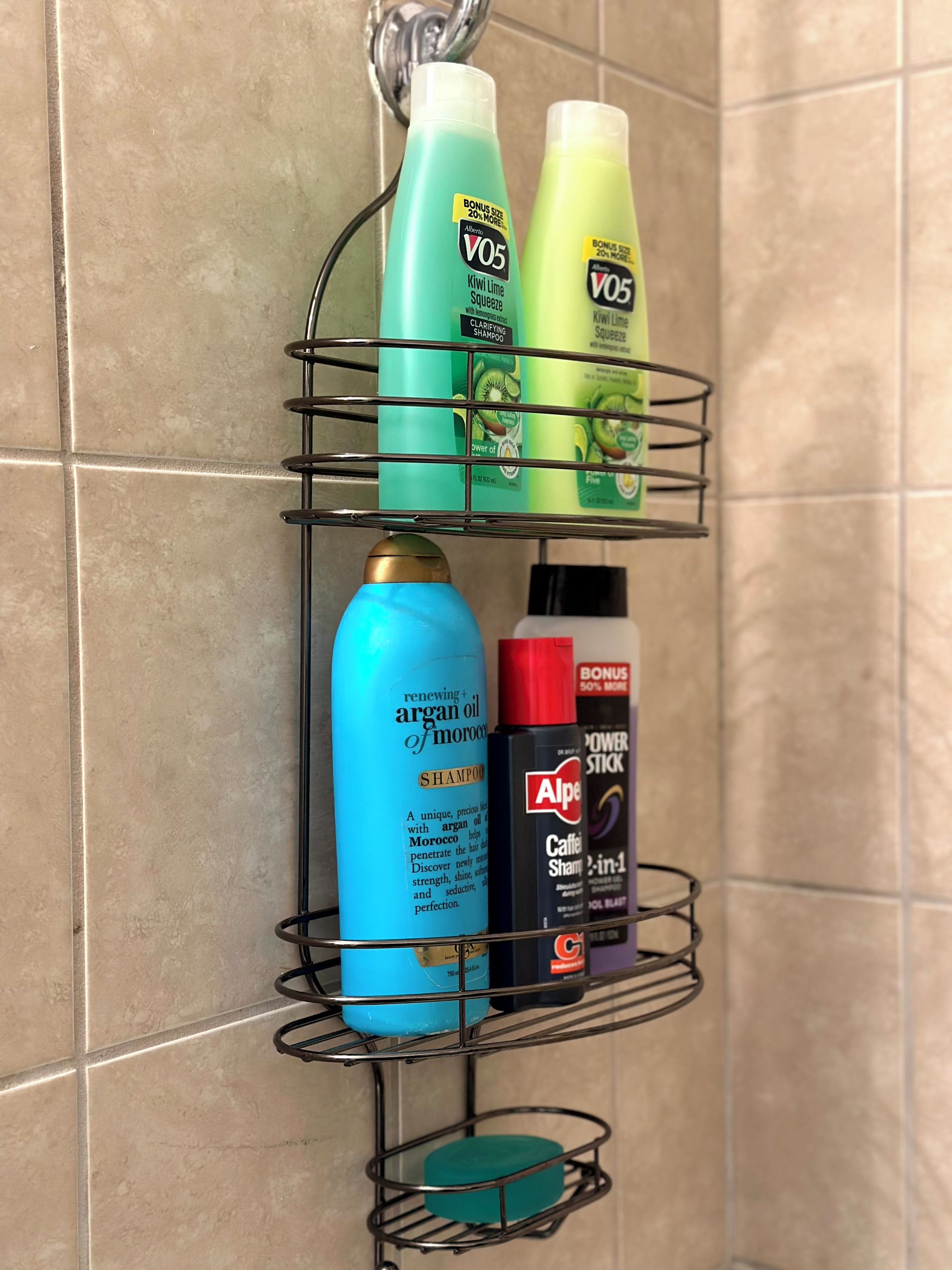 A bathroom shelf with various toiletries including a blue bottle of shampoo, a green bottle of lotion, and a black bottle of body wash.